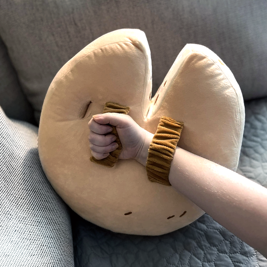 A model demonstrates the proper grip while holding the Wedge of Destiny Shield Pillow. Their wrist is slid through the first strap on the back, so their hand can grip the second strap.