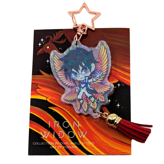 A product photo of Side 1 of the Shimin Holographic Charm. Shimin is illustrated with his hand extended to the side, wearing a black and white outfit and fiery-colored bird wings behind them. The charm has a star shaped clasp, a red tassel, and the acrylic has a holographic effect. The charm is attached to its backing card, which has an illustration of a red feathery phoenix with a glowing yellow eye.