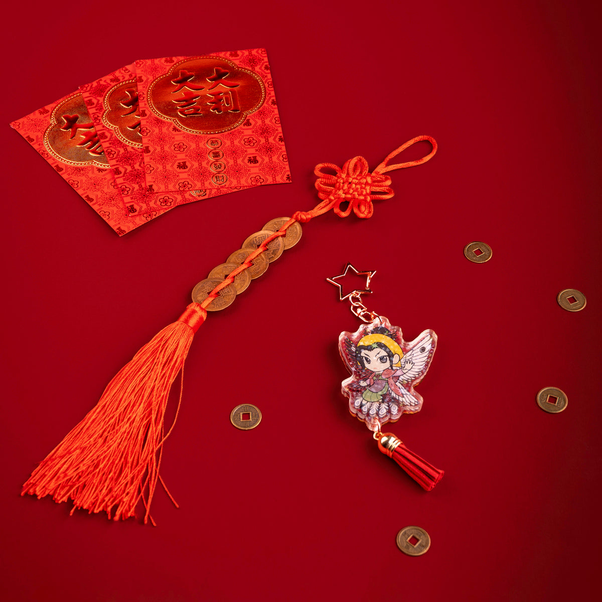 A photo from above of Side 2 of the Zetian Holographic Charm. Zetian illustrated with black and white yin and yang bird wings behind them and traditional, muted clothing. The charm has a star shaped clasp, a red tassel, and the acrylic has a holographic effect. The charm is surrounded by scattered coins.