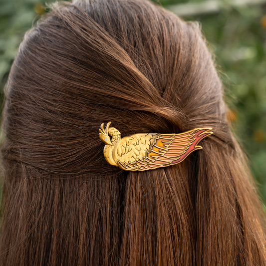 A model wearing the golden Vermillion Bird hair clip. It is pinning up the top section of their long, brown hair.
