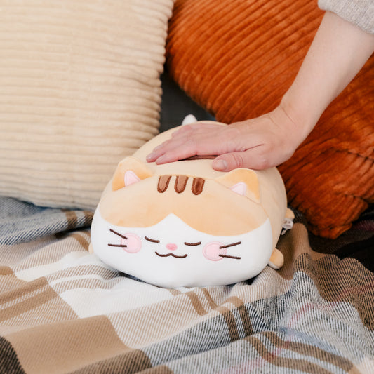 Bert plushie sits peacefully among blankets and pillows while a model's hand rests on its back.