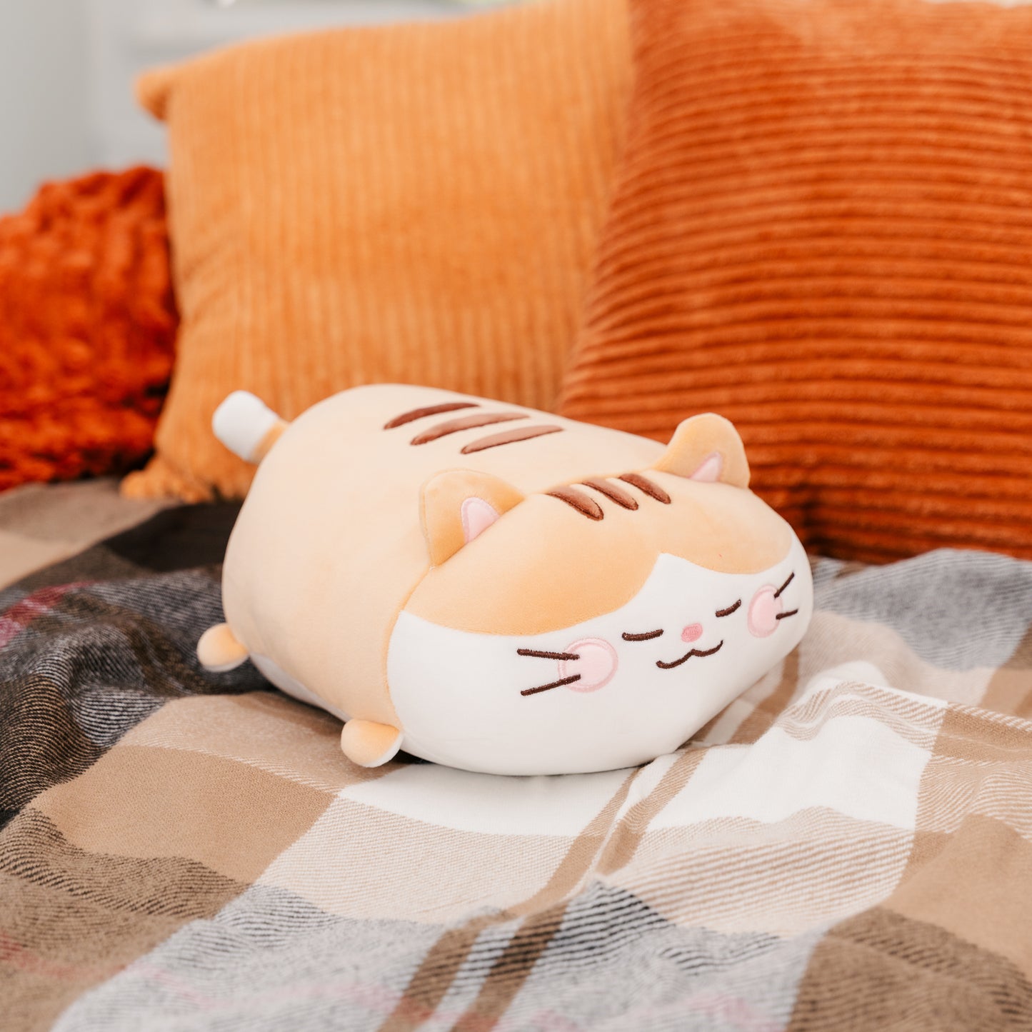 Bert plushie rests on a plaid blanket among pillows.