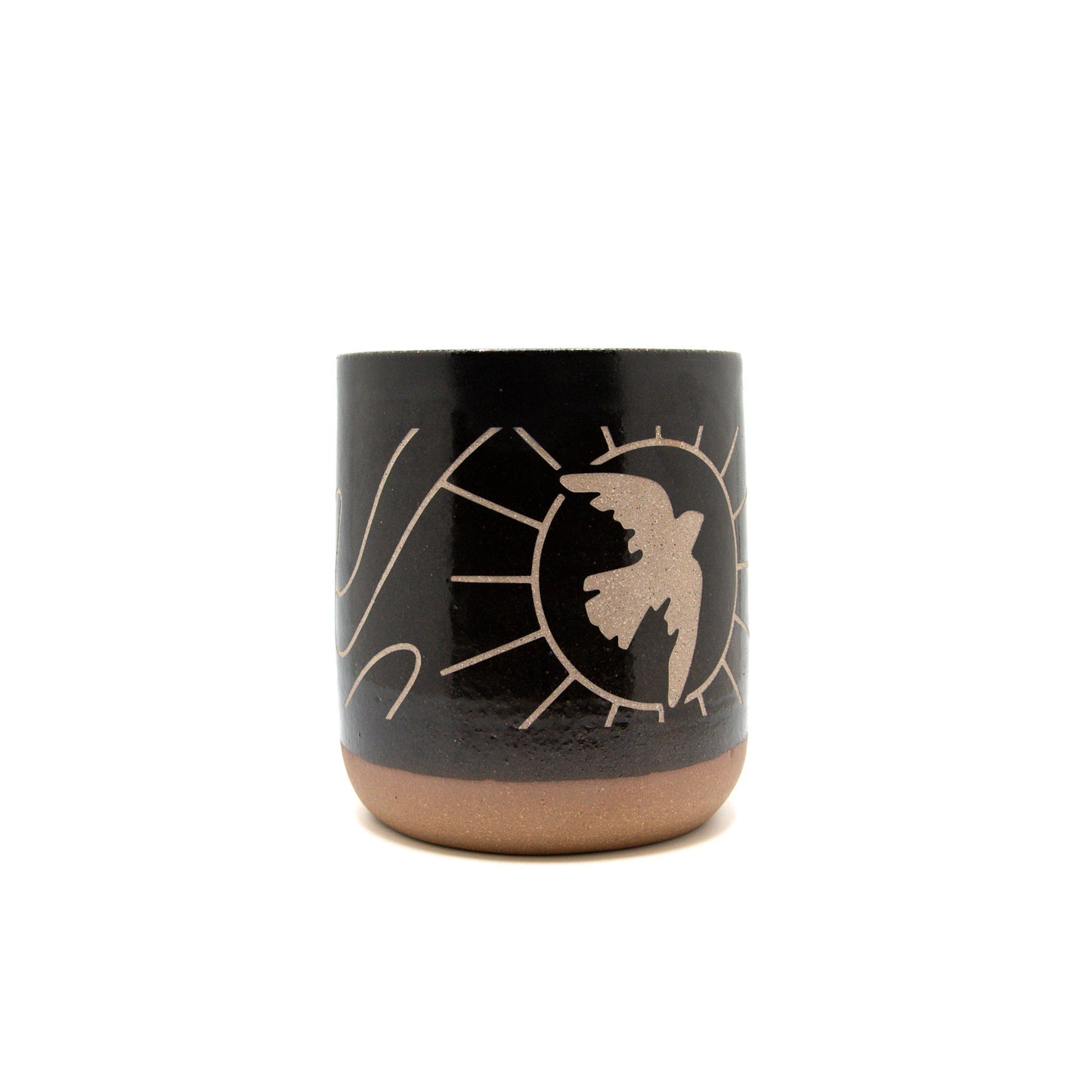A product photo of the dancing dove sandcarved mug. The mug is black slip with carved details showing a dove's silhouette soaring across a sun. There is swirling lineart carved out of the slip around the rest of the mug.