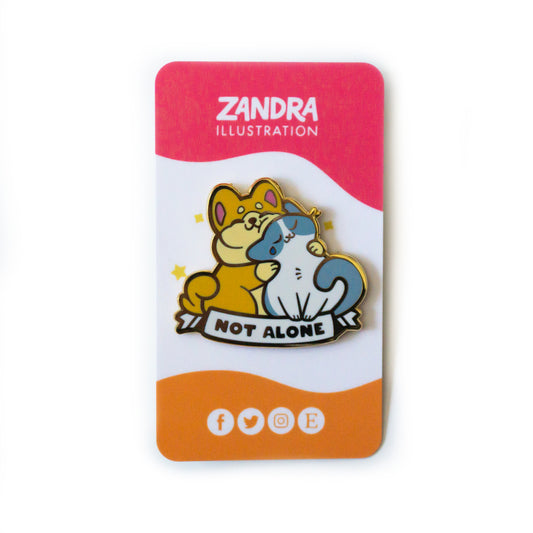 A product photo of the Not Alone Pin on its magenta, white, and orange wavy colorblocked backing card. The backing card says Zandra Illustration at the top in white, and displays icons that signify the artist is on facebook, twitter, instagram, and etsy along the bottom of the card.