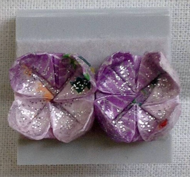 Sparkly violet paper lotus earrings on white background
