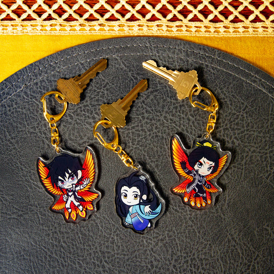 All three Iron Widow character charms side one, attached to house keys on a black pebbled leather mat.