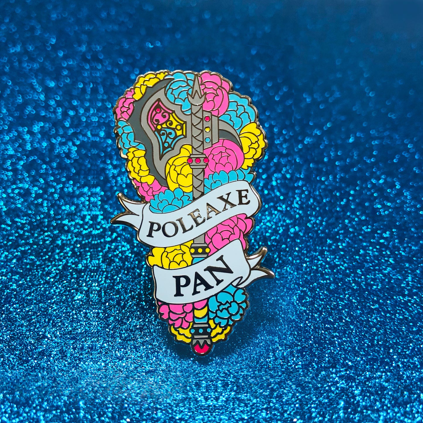 The goldcast pin features a decorative poleaxe in a bed of roses in the blue, yellow, and pink colors of the pansexual flag. A ribbon trails across the front and reads "Poleaxe Pan."