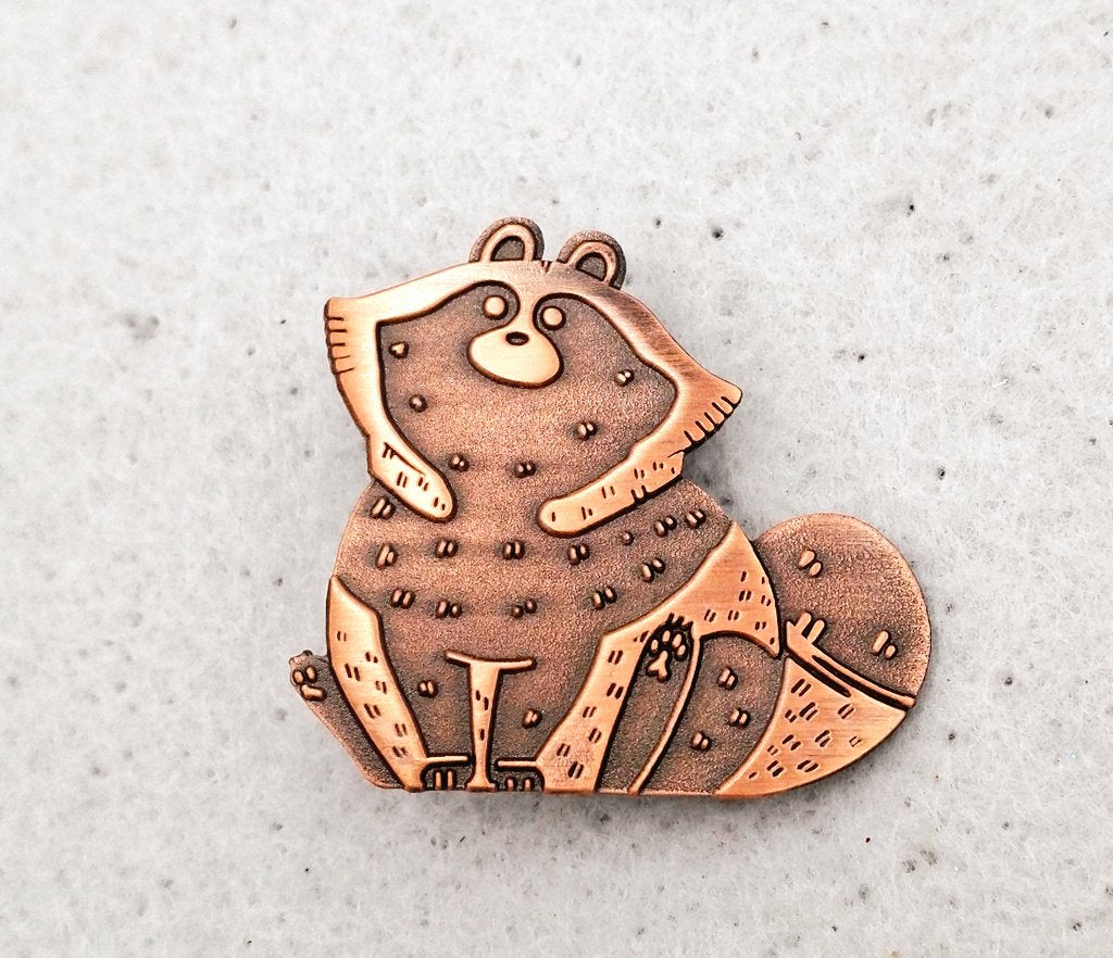 Front view of tanuki enamel pin.