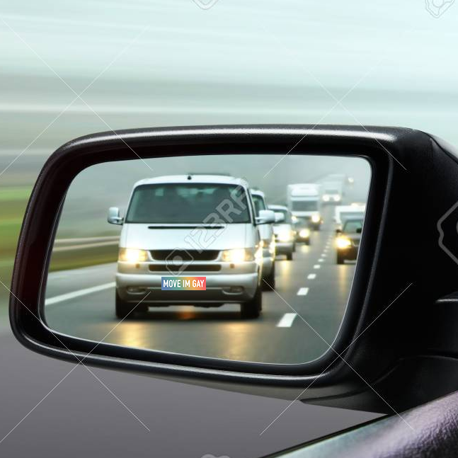 The move I'm gay bumper sticker is on the front of a silver van, being viewed from the driver's side rearview mirror perspective.