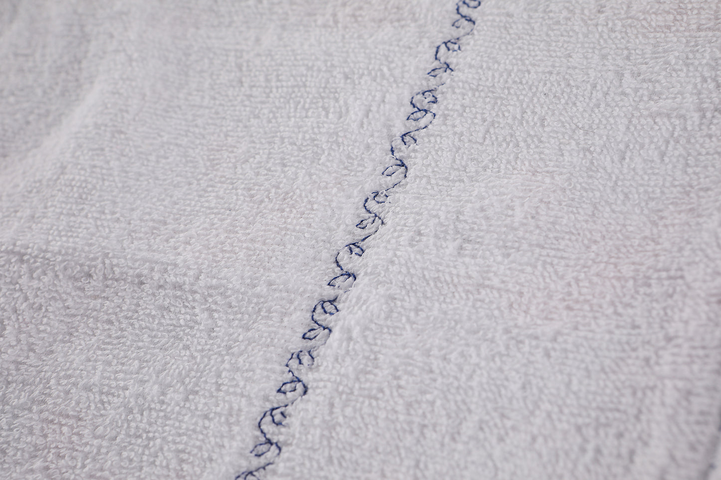 Closeup of white lining, sewn with decorative leafy vine stitch.