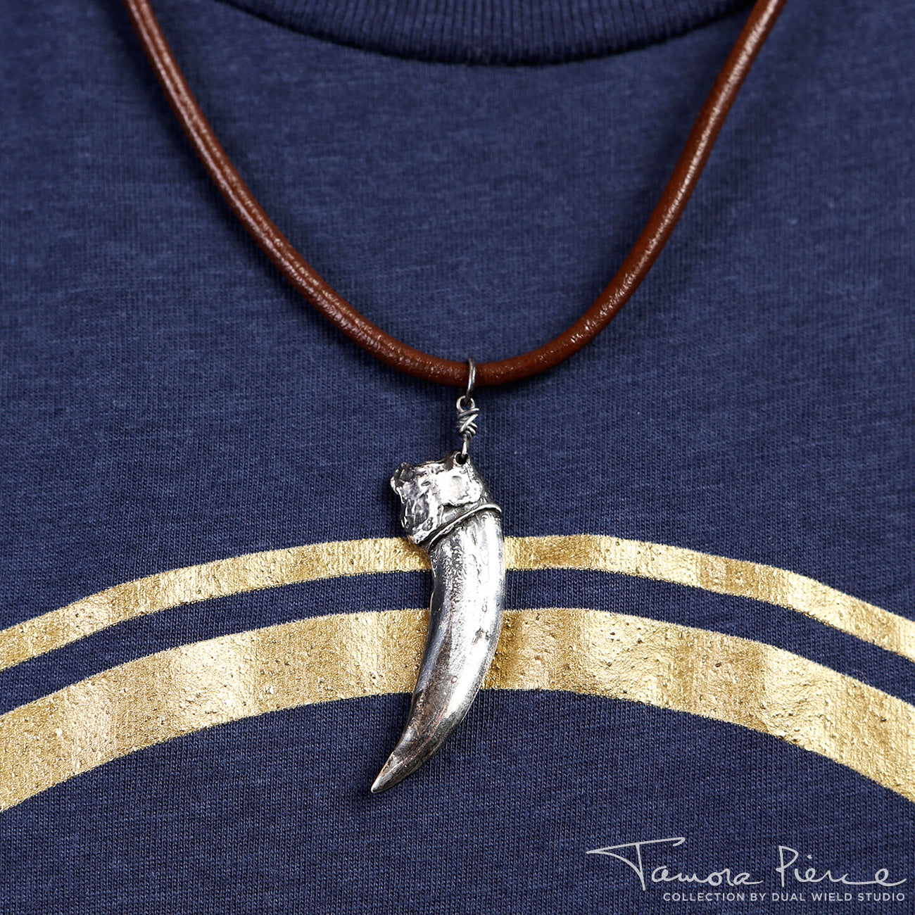 Model wearing silver badger claw pendant on brown necklace cord.