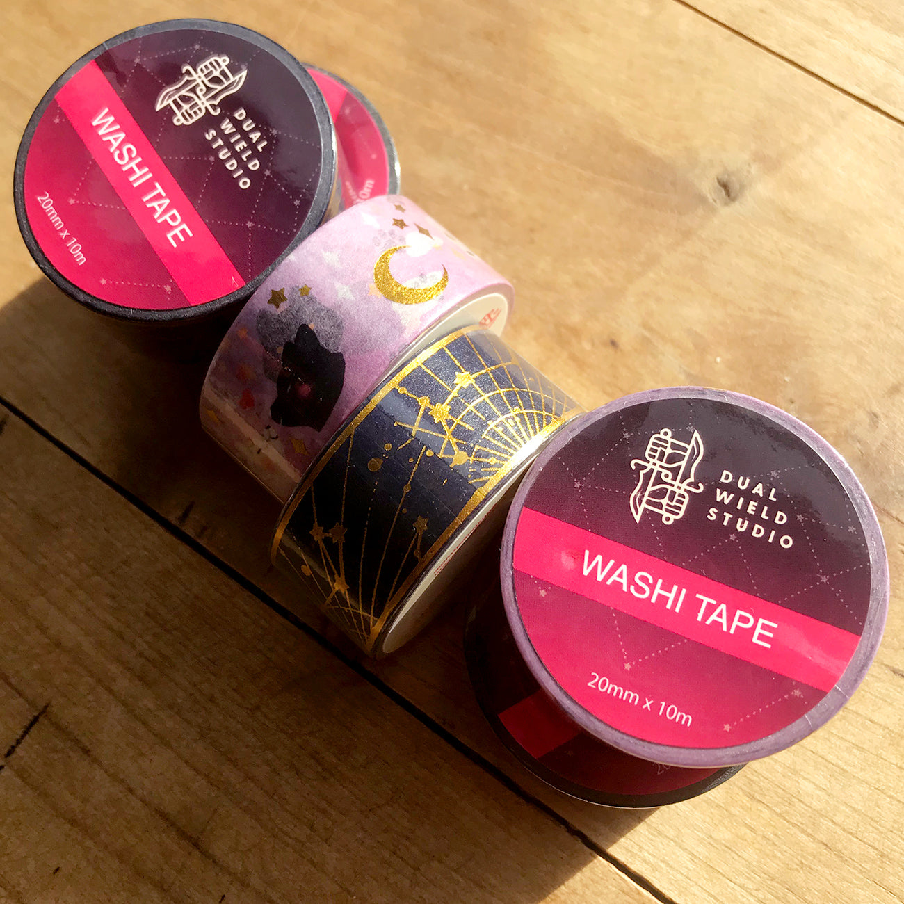 Bundle of six different Dual Wield Studio washi tapes on wooden table.