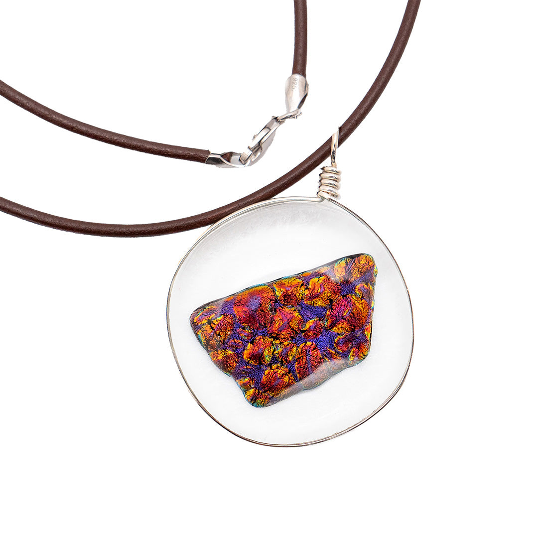 close up of the pendant, which is round and clear with an irregularly shaped, multi-colored "ember" inside.