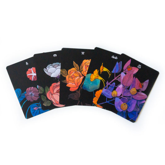   A five card spread of tarot cards depicting various botanical elements, all with black backgrounds and colorful paintings of plants. White symbols at the top center of each card denote its tarot suit.