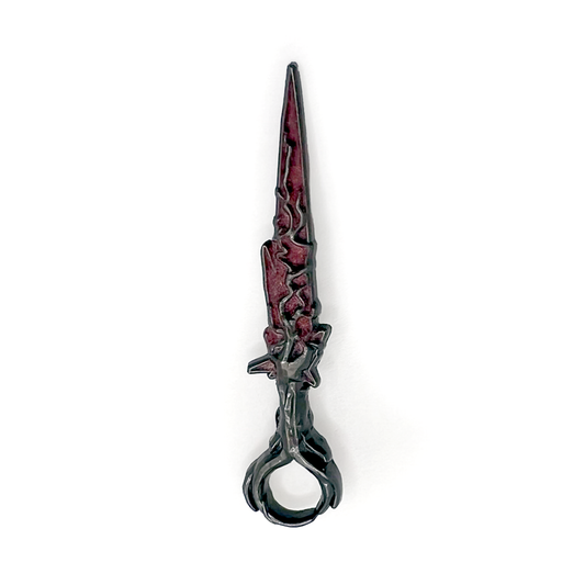 A product photo of the Red Lyrium Dagger Enamel Pin. The blade of the dagger is craggy and burgundy red. The hilt is gunmetal and textured.