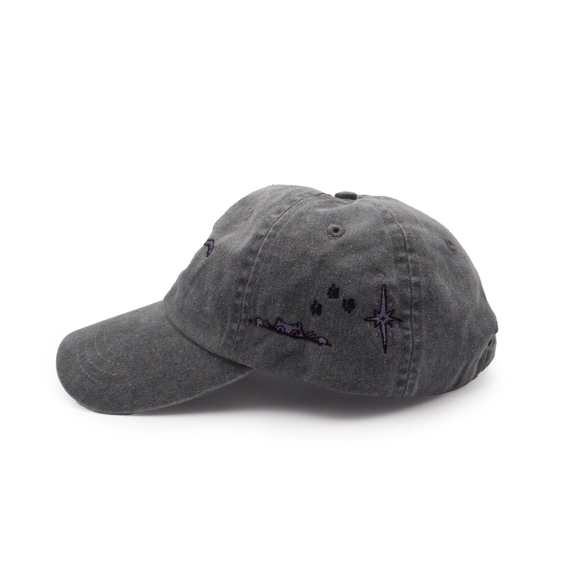 A left side view of the black Faithful embroidered hat. On the left side, an additional Faithful peeks up from an embroidered line. Black embroidered paw prints walk toward her followed by an embroidered purple shining star.