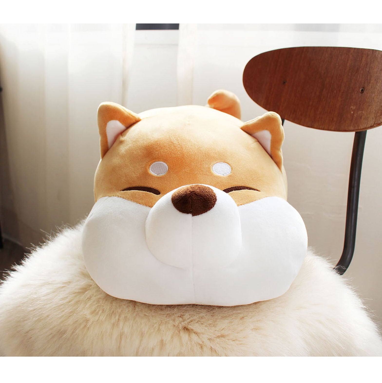 Front view of Shiba Cushion resting on a wooden chair with white fur blanket.