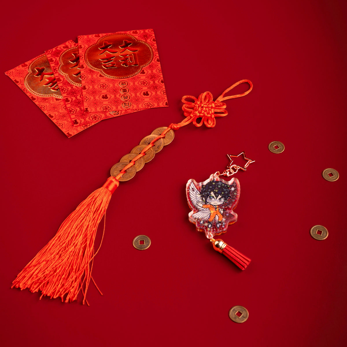 A photo from above of Side 2 of the Shimin Holographic Charm. Shimin is illustrated with his hand extended to the side, wearing an orange outfit and black and white bird wings behind them. The charm has a star shaped clasp, a red tassel, and the acrylic has a holographic effect. The charm is surrounded by scattered coins.