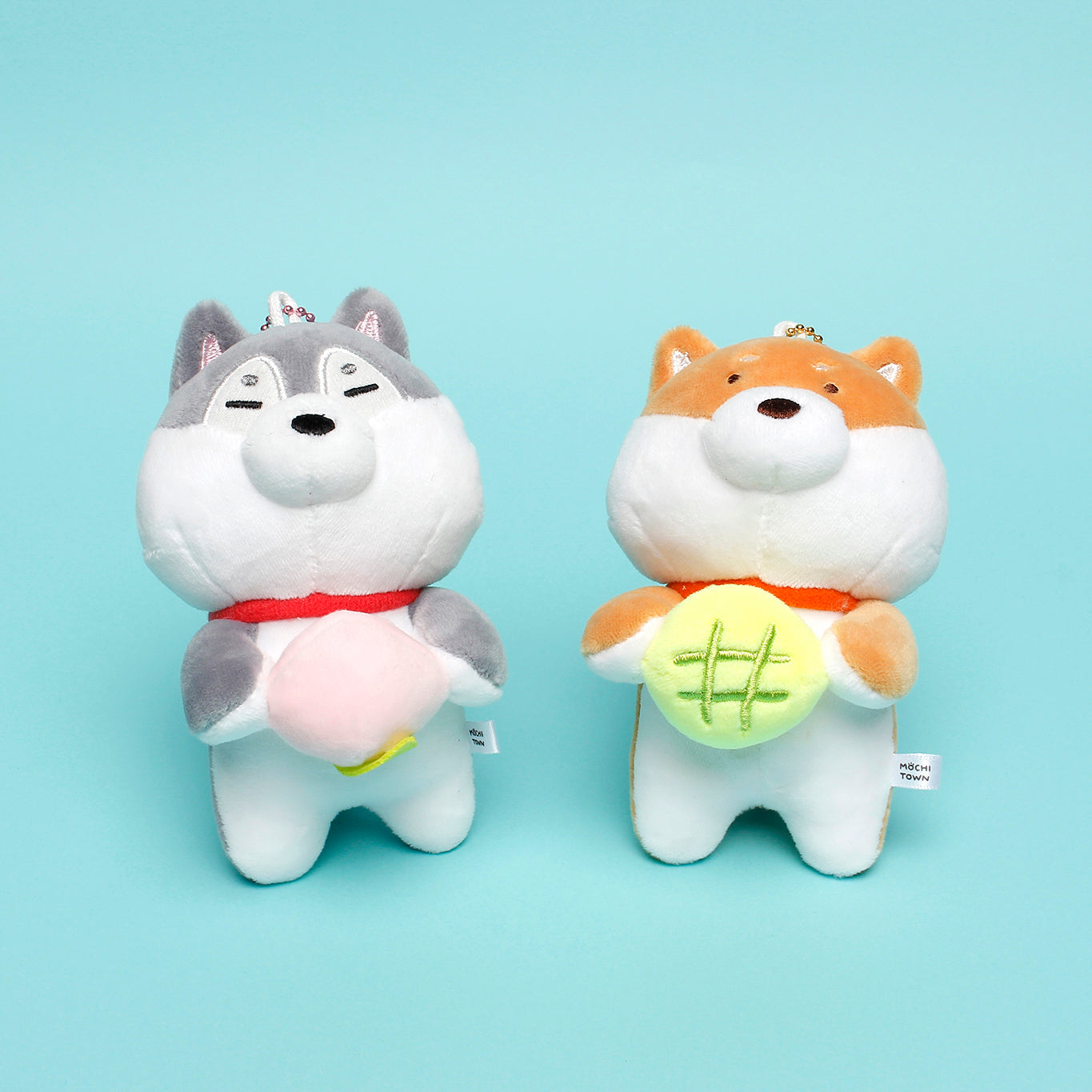 Two keyring dogs sit together on teal background.