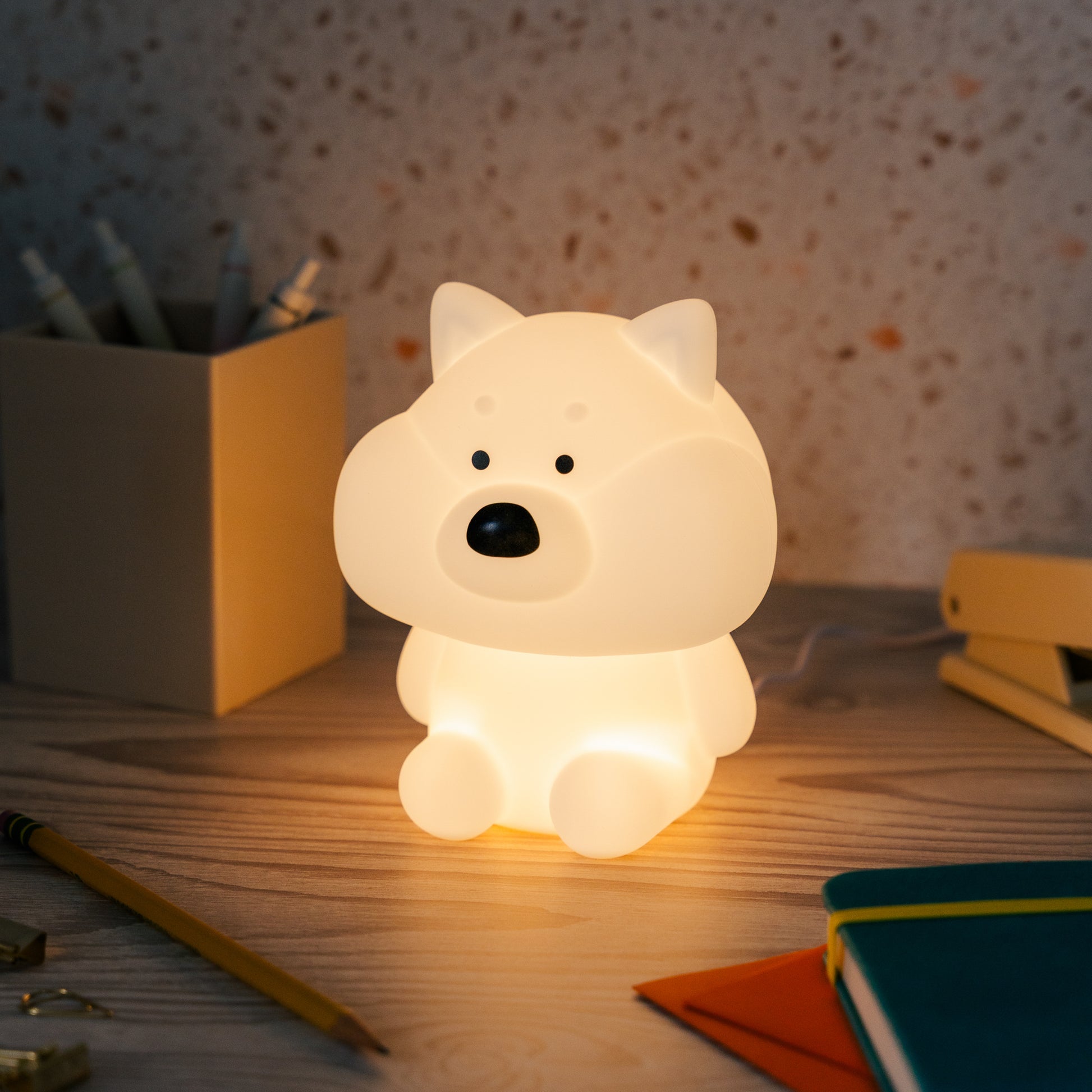 Shiba mood lamp softly brightens a dark room on a desk with clutter.