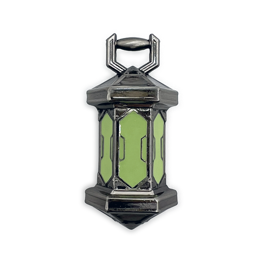 A product photo of the Gloaming Lantern Pin. The pin is cast in silver metal, and the three panes of the lantern are a bright foresty green. 