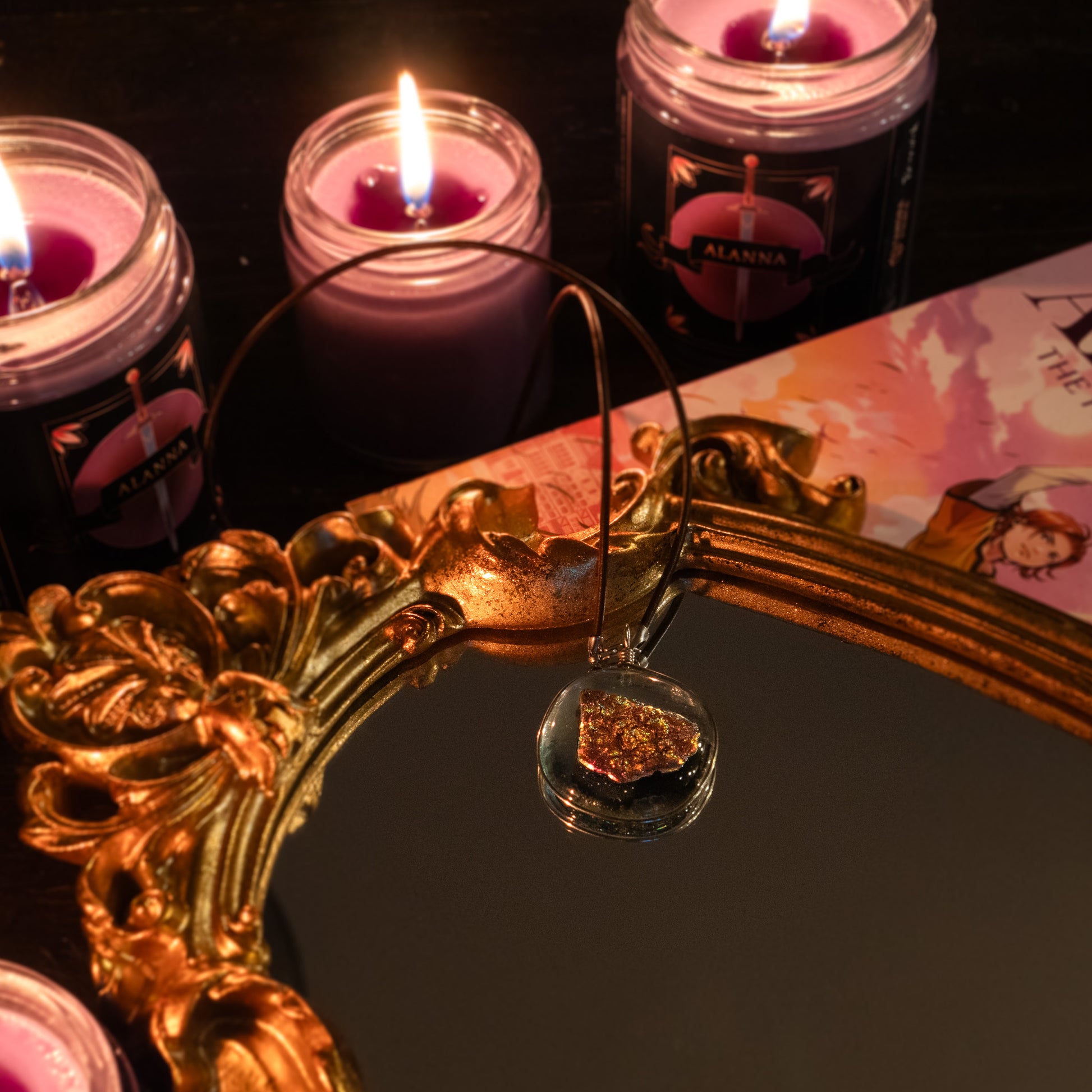 the ember glass pendant lying on a mirror, surrounded by candles.