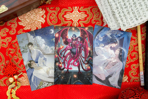 The Iron Trio Postcard set displayed on red and gold silk. 