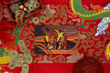 Load image into Gallery viewer, Vermilion Bird Enamel Pin with an Iron Widow card backing on an elaborate red table runner surrounded by decorations.