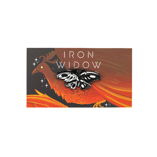 Sparkling black and white butterfly enamel pin on red phoenix backing card with Iron Widow logo.