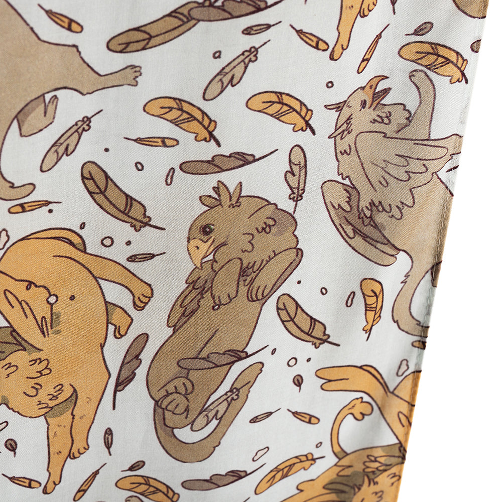 Closeup of Tamora Pierce: Griffins Scarf showing beige and tan griffin sprawling among feathers and other posing griffins.