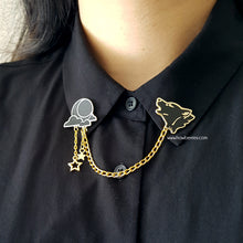 Load image into Gallery viewer, The white variation of Wolf &amp; Moon collar pins on model wearing black button up. Black wolf howling enamel pin is connected to black moon and clouds by golden delicate chain with tiny star charms.
