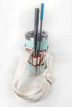 Load image into Gallery viewer, Linen color cloth cup holder with Baker Bunneh as an embroidered patch holding a mint green coffee tumbler and metal straw.