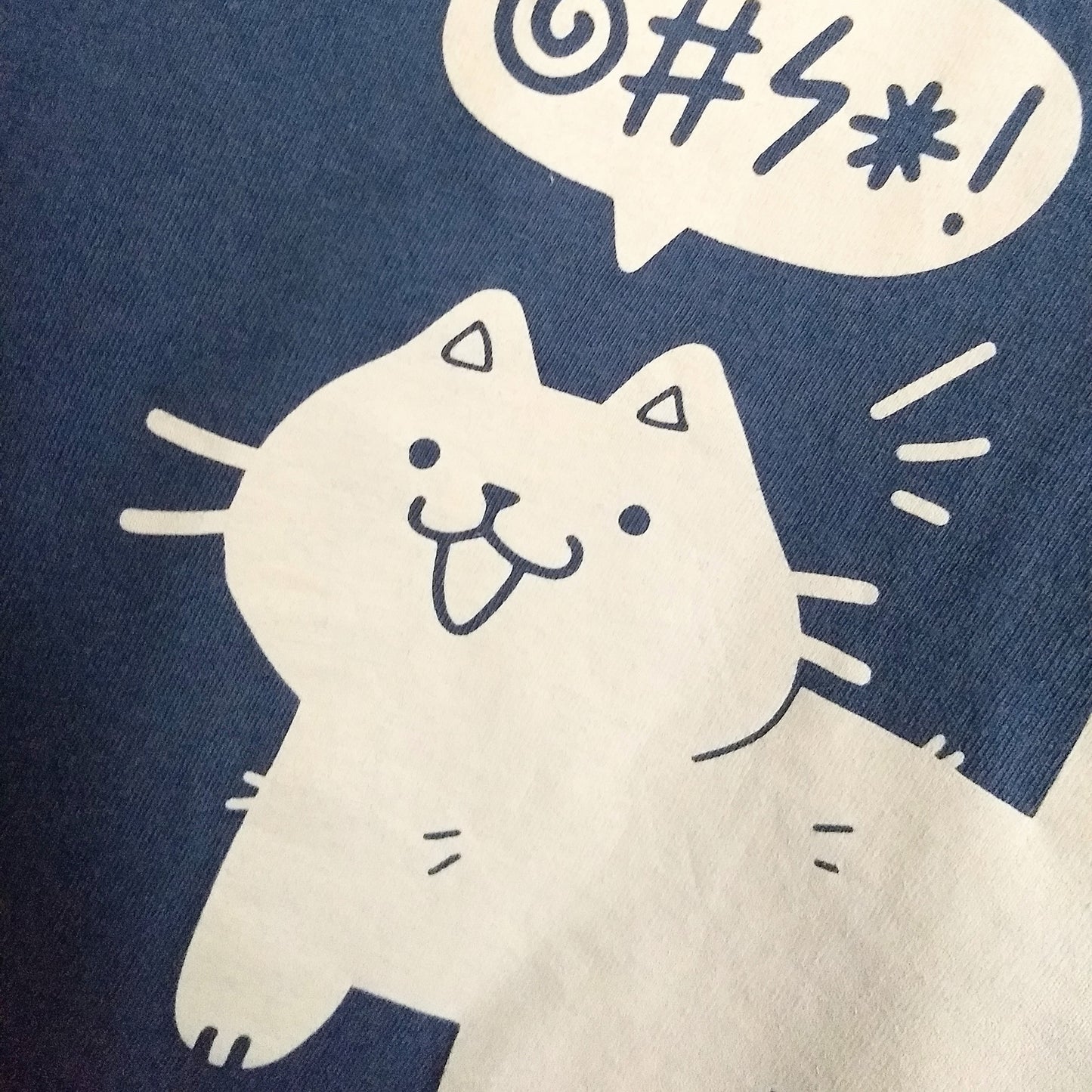 Closeup of the white printed cat and speech bubble on the t-shirt.