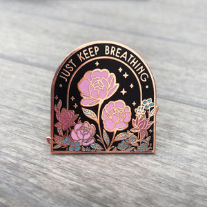 Front view of rose gold flowers pin with text that reads "Just Keep Breathing."