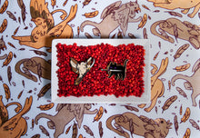Load image into Gallery viewer, Tamora Pierce Faithful with Sword pin and Keladry Crown Sparrow pin together in a white bowl filled with red beads on Tamora Pierce: Griffin Scarf background.
