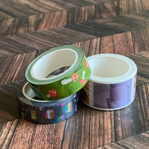 The Deadly Fungi washi tape is featured among two other washi tapes in a pile on a wooden table.