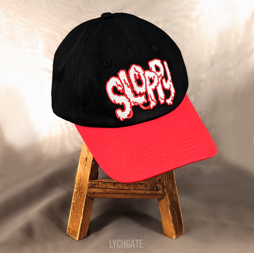 The SLOPPY baseball cap is a black cap with a red brim. SLOPPY in goopy white letters and red outlines is embroidered on the front of the cap.