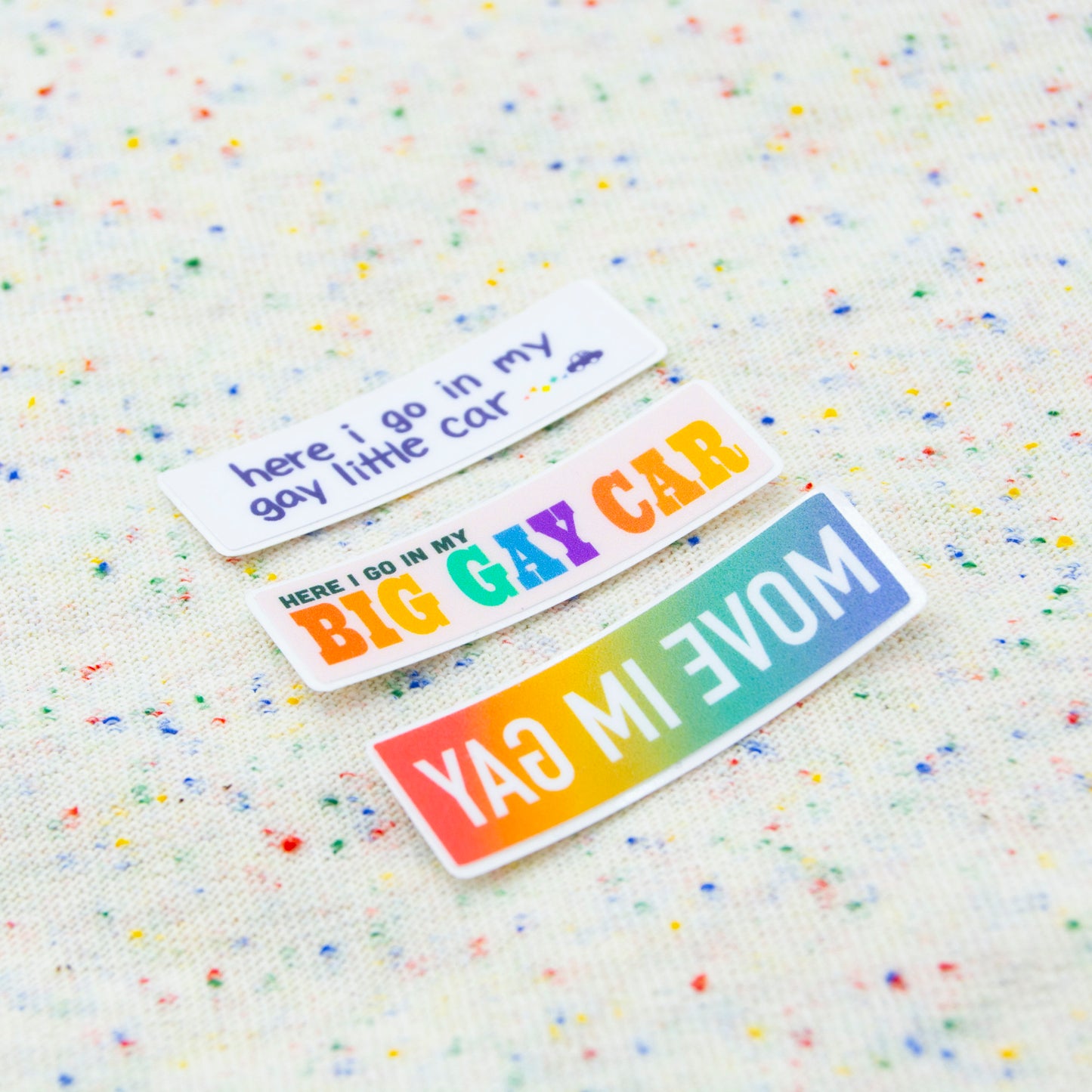 All three mini stickers at an angle together on a funfetti fabric background.