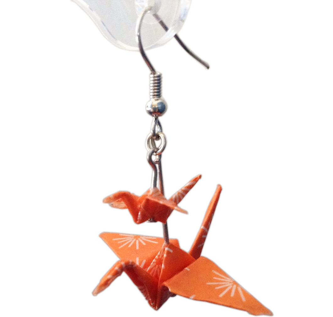 Orange paper crane earring on white background