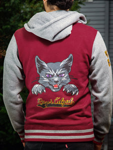 Back of Faithful varsity zip up hoodie on model in front of grey house with green shrubbery.
