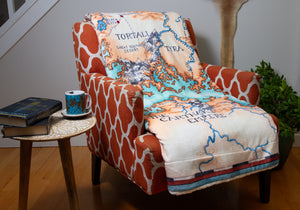 A folded Tortall blanket draped over a chair, showing a large portion of the illustration.
