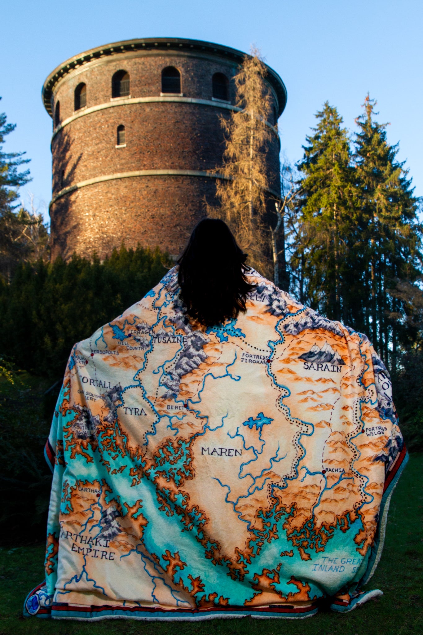 A view of a person from behind, wearing the Tortall blanket like an outstretched cape.