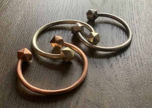 Rose gold, bronze, and silver D20 Dice bangle on wooden table.