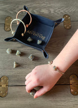 Load image into Gallery viewer, Bronze D20 Dice Bangle on model rolling dice on a wooden chest.