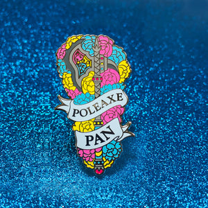 The goldcast pin features a decorative poleaxe in a bed of roses in the blue, yellow, and pink colors of the pansexual flag. A ribbon trails across the front and reads "Poleaxe Pan."