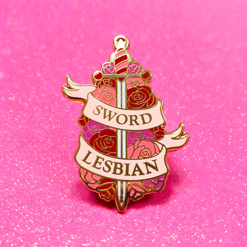 The goldcast pin features an ornate sword in a bed of roses in the orange and pink colors of the lesbian flag. A ribbon trails across the front and reads 