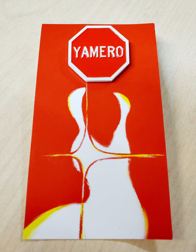 Front view of yamero enamel pin on red backing card on wood background.
