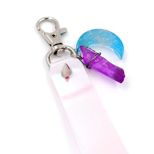 Closeup of Holographic keystrap with silver clasp and blue moon charm on white background.