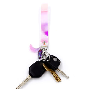 Holographic keystrap with silver clasp and pink moon charm with various keys attached on white background.