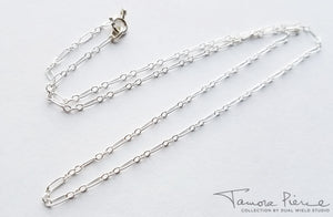 Silver necklace chain on white background.